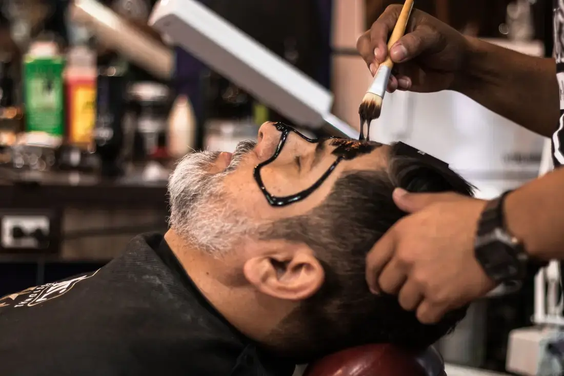 A guest leaning back in the chair as a face mask is brushed on
